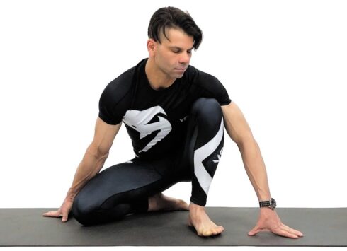 Man performing seated yoga pose on mat.