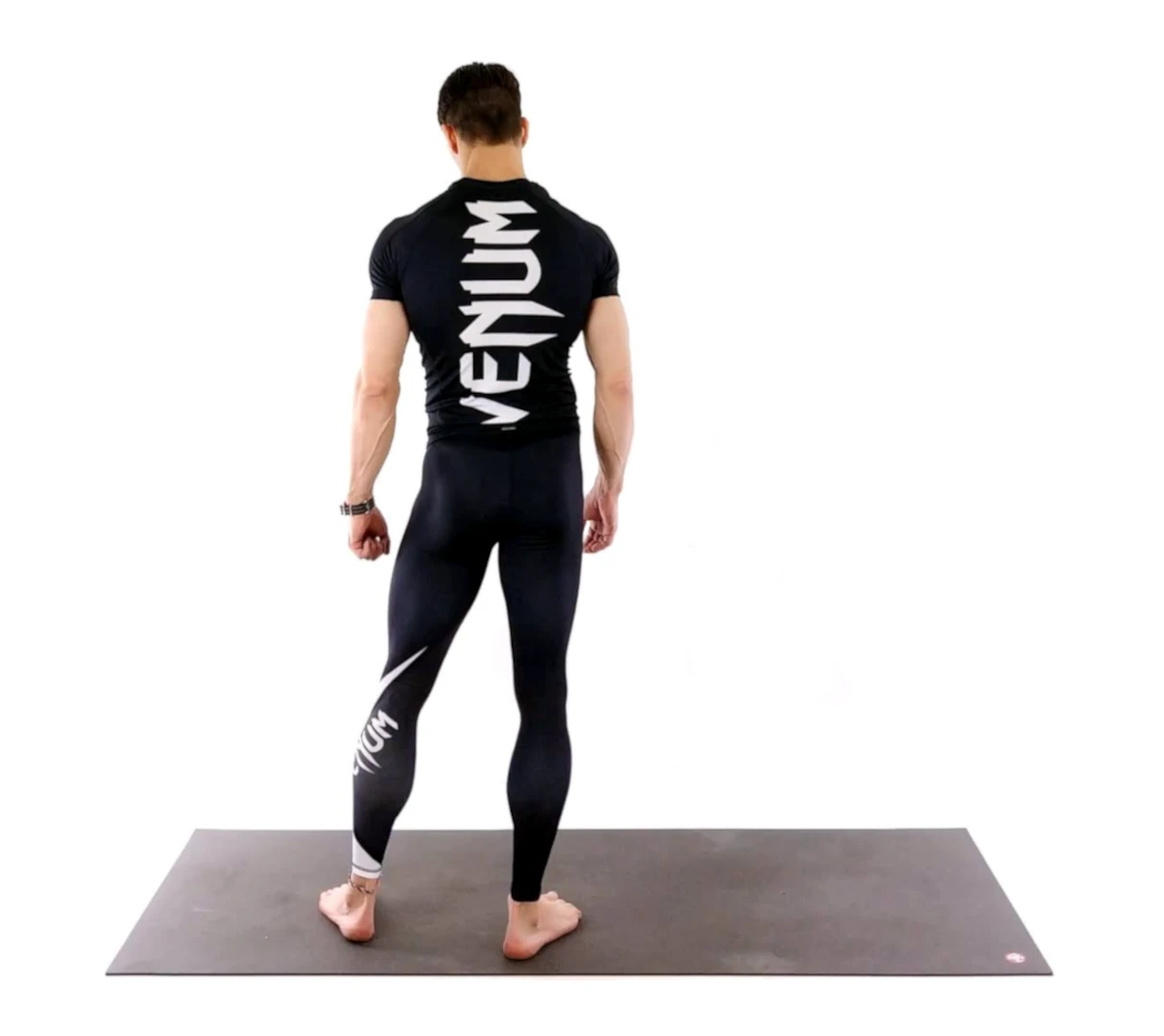 Man in athletic gear standing on mat.